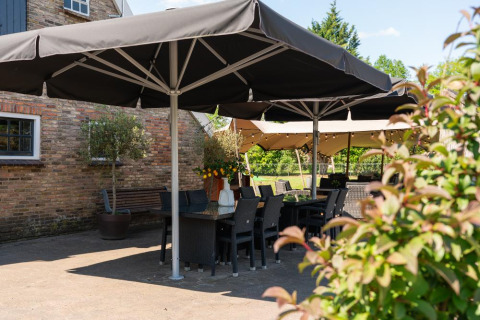 Zona de comedor al aire libre con sombrillas negras en Holiday Resort 't Schuttenbelt en Overijssel, Países Bajos.