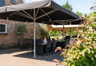 Außenbereich mit Tischen, Stühlen und Sonnenschirmen im Holiday Resort 't Schuttenbelt in Overijssel, Niederlande.
