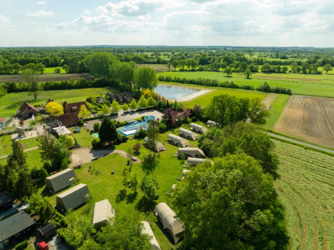 Aerial view of Holiday Resort 't Schuttenbelt in Overijssel, Netherlands, with tents, pool and green fields.