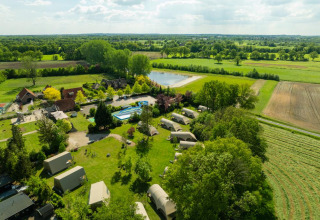 Aerial view of Holiday Resort 't Schuttenbelt in Overijssel, Netherlands, with tents, pool and green fields.