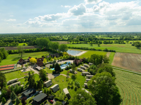 Vista aérea del Holiday Resort 't Schuttenbelt en Overijssel, Países Bajos, con campos, piscina y tiendas.