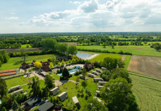 Luftfoto af ferieparken 't Schuttenbelt i Overijssel, Holland, med grønne marker, swimmingpool og telte.