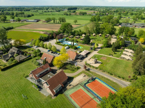 Vista aérea del Holiday Resort 't Schuttenbelt en Overijssel, Países Bajos, con canchas de tenis, piscina y tiendas.