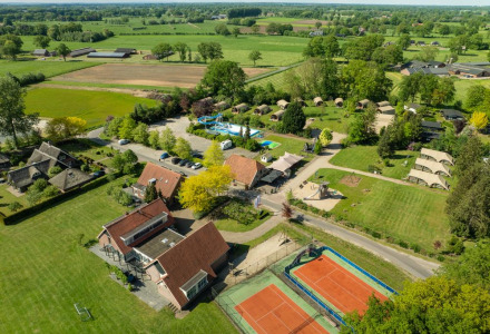 Luchtfoto van Holiday Resort 't Schuttenbelt in Overijssel, Nederland, met tennisbanen, zwembad en tenten.