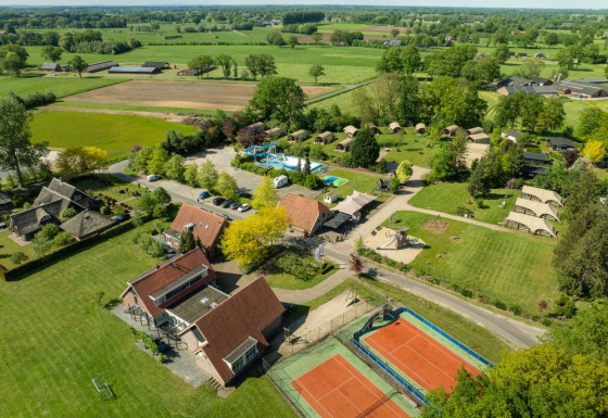 Vue aérienne du Holiday Resort 't Schuttenbelt à Overijssel, Pays-Bas avec terrains de tennis, piscine et tentes.