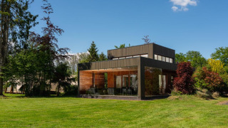 Moderne tiny house Woody Lodge Valerie bij Holiday Resort 't Schuttenbelt, omgeven door gras en bomen.