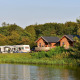 Udsigt over søen mod River Cottage lodges og campingvogne ved Camping de Koeksebelt i Holland.