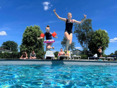 Dos niños saltan a una piscina en Vakantiepark de Zeeuwse Parel, Zelanda, Países Bajos, en un día soleado.