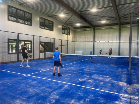Quattro persone giocano a padel su un campo coperto a Vakantiepark de Zeeuwse Parel, Zelanda, Paesi Bassi.