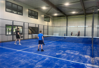 Fire personer spiller padeltennis på en indendørs bane i Vakantiepark de Zeeuwse Parel, Zeeland, Holland.