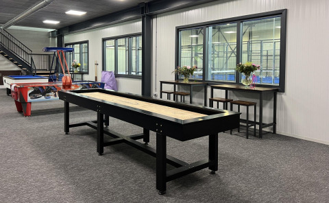 Sala de juegos en Vakantiepark de Zeeuwse Parel, Zeeland, con shuffleboard, hockey de aire y mesas altas.