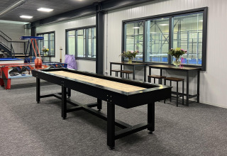 Espace loisirs intérieur au Vakantiepark de Zeeuwse Parel, Zeeland avec shuffleboard, air hockey et tables hautes.