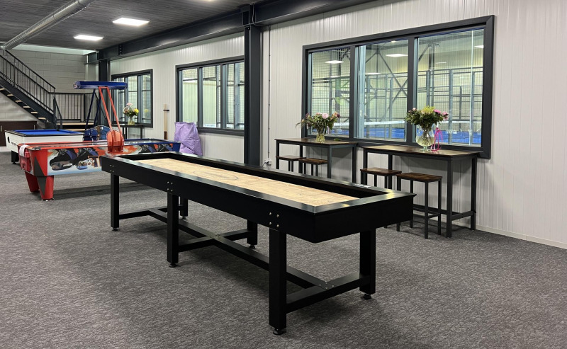 Freizeitraum im Vakantiepark de Zeeuwse Parel, Zeeland, mit Shuffleboard, Airhockey und Bartischen.