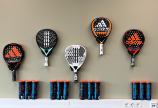 Adidas padelrackets en ballenblikken aan de muur in een vakantiepark in Zeeland, Nederland, tentoongesteld.