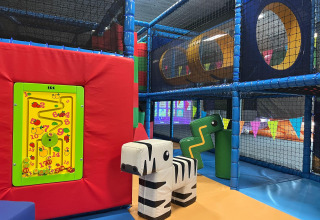 Aire de jeux intérieure pour enfants avec structures d’escalade souples, toboggans et jeux colorés.