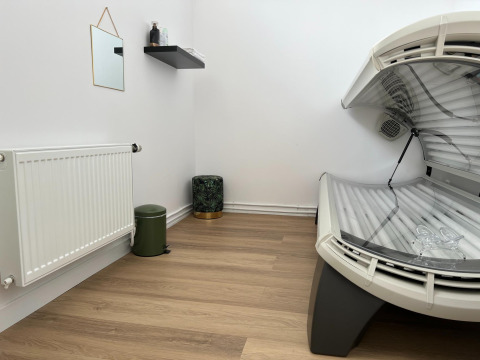 Et værelse med en solariebænk, radiator, lille spejl og hylde på væggen i et feriepark i Zeeland.