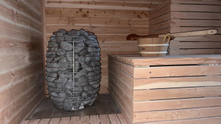 Sauna con piedras calientes y un balde de madera en Vakantiepark de Zeeuwse Parel, en Zelanda, Países Bajos.