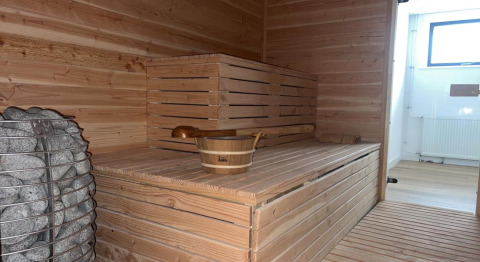Sauna interior con bancos de madera y piedras, en Vakantiepark de Zeeuwse Parel en Zelanda, Países Bajos.