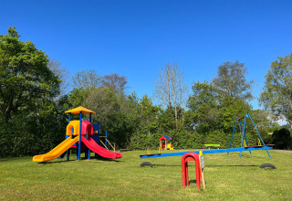 Spielplatz mit Rutschen, Schaukeln und Wippen im Vakantiepark de Zeeuwse Parel, Zeeland, Niederlande, bei Sonne.