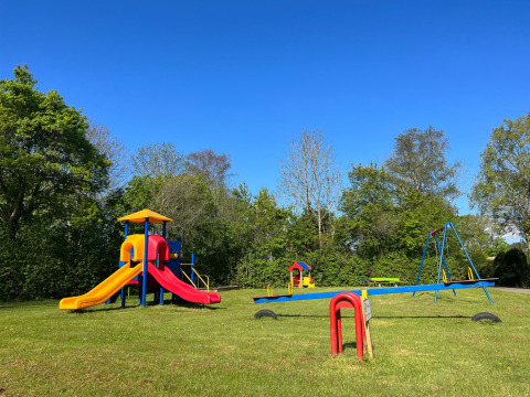 Spielplatz mit Rutschen, Schaukeln und Wippen im Vakantiepark de Zeeuwse Parel, Zeeland, Niederlande, bei Sonne.