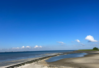 Uitgestrekt kustlandschap bij Vakantiepark de Zeeuwse Parel in Zeeland, Nederland, met een heldere blauwe lucht.