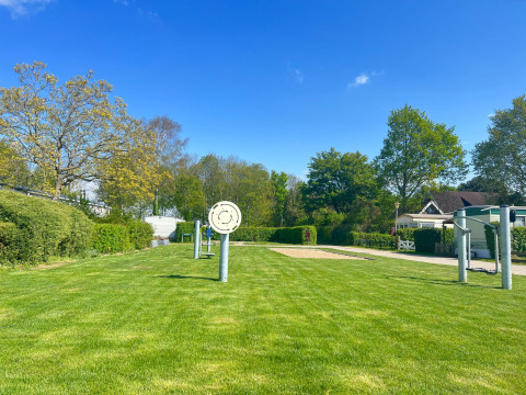 Groen gazon met speeltoestellen en vakantiehuisjes aan Vakantiepark de Zeeuwse Parel in Zeeland.