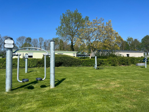 Attrezzi per il fitness all'aperto sull'erba al Vakantiepark de Zeeuwse Parel, Zeeland, Paesi Bassi in una giornata soleggiata.