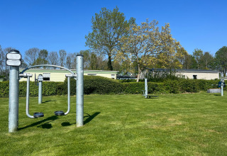 Buitensporttoestellen op het grasveld bij Vakantiepark de Zeeuwse Parel, Zeeland, Nederland onder een blauwe lucht.