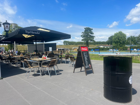 Area caffè all’aperto con ombrelloni vicino a una piscina al Vakantiepark de Zeeuwse Parel, Zeeland.