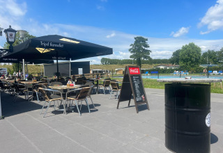 Terrasse de café en plein air avec parasols près d'une piscine au Vakantiepark de Zeeuwse Parel, Zeeland.