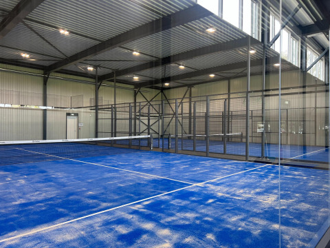 Indendørs padelbane med blå overflade og sorte metalgitre, set på Vakantiepark de Zeeuwse Parel i Zeeland.