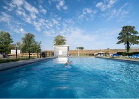 Freiluft-Schwimmbad mit klarem Wasser im Vakantiepark de Zeeuwse Parel in Zeeland, Niederlande, unter blauem Himmel.