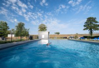 Freiluft-Schwimmbad mit klarem Wasser im Vakantiepark de Zeeuwse Parel in Zeeland, Niederlande, unter blauem Himmel.