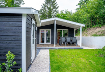 Familie-lodge med sort træbeklædning og terrasse med spisebord, ligger ved De Thijmse Berg i Holland.