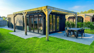 Moderne Eco Lodge ved Uniq Leisure i Holland med store vinduer, træterrasse og udendørs spiseområde.
