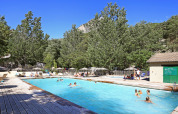 Udendørs swimmingpool omgivet af træer og ferieboliger ved Huttopia Gorges du Verdon på en solrig dag.