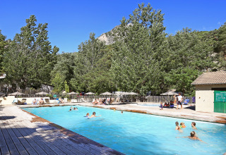 Freibad im Huttopia Gorges du Verdon Ferienpark, umgeben von Natur und Bäumen an einem sonnigen Tag.