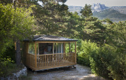 En hyggelig træhytte i en skov ved Huttopia Gorges du Verdon, med udsigt til bjergene i Hauts-de-France.
