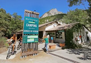 Cykler og gæster nyder sommeren ved Huttopia Gorges du Verdon campingplads, omgivet af bjerge og skov.