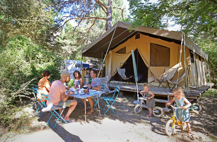 Famille prenant le petit-déjeuner en plein air devant une grande tente à Huttopia Gorges du Verdon, France.