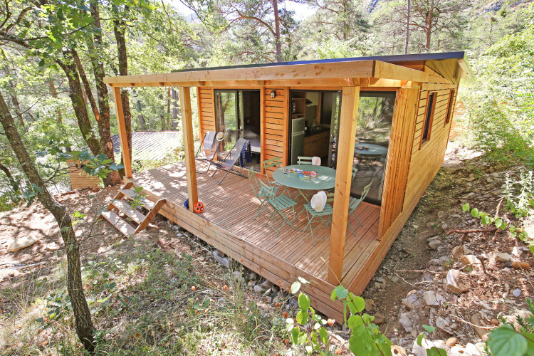 Eine moderne Glamping-Hütte aus Holz mit Veranda inmitten eines ruhigen Waldes im Ferienpark.