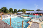 Udendørs poolområde med børn, vandleg og overdækket swimmingpool på Huttopia Baie du Mont St Michel.