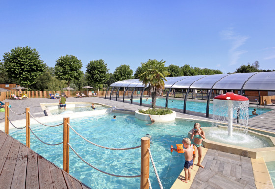 Udendørs poolområde med børn, vandleg og overdækket swimmingpool på Huttopia Baie du Mont St Michel.