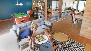 Familia disfruta de juegos y actividades en el salón común de Huttopia Baie du Mont St Michel, Bretaña.