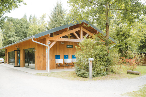 Edificio de madera rodeado de árboles en Huttopia Baie du Mont St Michel, parque vacacional en Bretaña, Francia.