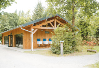 Edificio in legno circondato da alberi presso Huttopia Baie du Mont St Michel, villaggio vacanze in Bretagna, Francia.