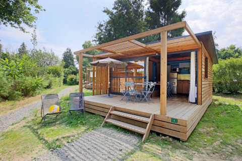 Udendørsbillede af Chalet Evasion træhytte med overdækket terrasse, havemøbler og grønne omgivelser
