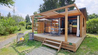 Udendørsbillede af Chalet Evasion træhytte med overdækket terrasse, havemøbler og grønne omgivelser