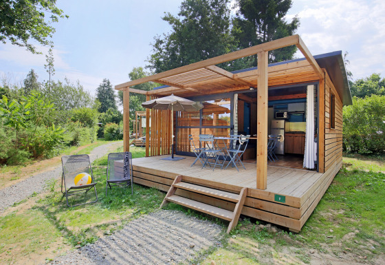 Udendørsbillede af Chalet Evasion træhytte med overdækket terrasse, havemøbler og grønne omgivelser