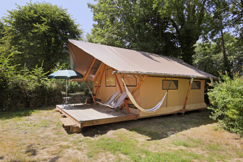 Tienda safari Trappeur Tent en Huttopia Baie du Mont St Michel, Francia, con terraza, hamaca y sillas.